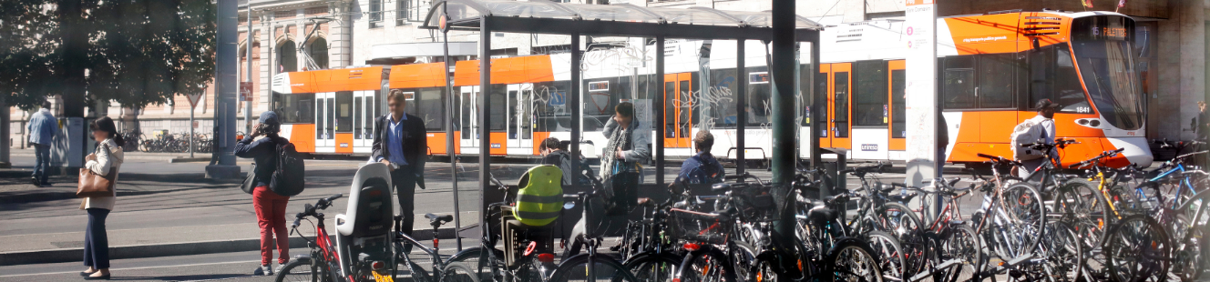 Photo d'un parking vélo à un arrêt de bus, avec un tram tpg